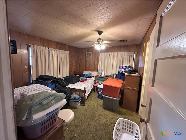 bedroom with carpet floors, wooden walls, and ceiling fan