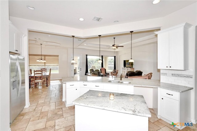 kitchen featuring a center island, a sink, ceiling fan, stainless steel fridge with ice dispenser, and visible vents