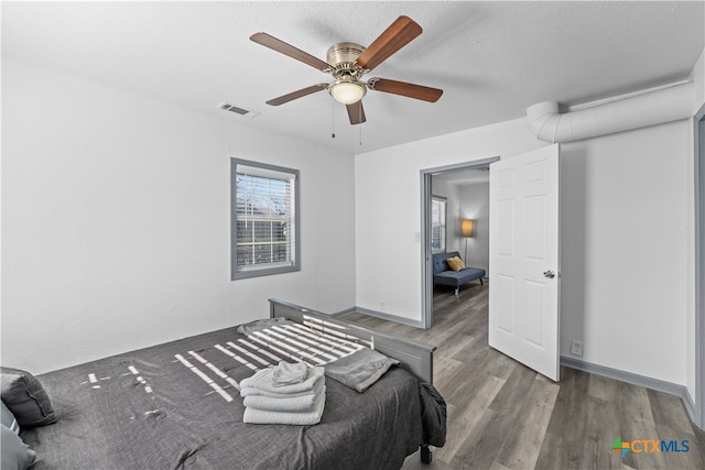 bedroom with a textured ceiling, wood-type flooring, and ceiling fan