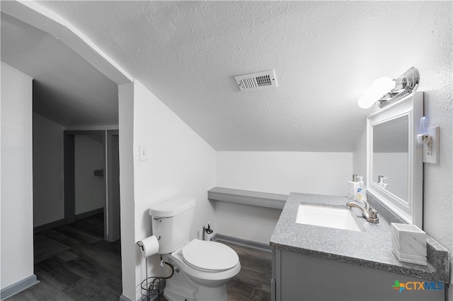 bathroom featuring wood-type flooring, vanity, a textured ceiling, vaulted ceiling, and toilet