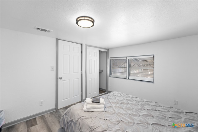 bedroom with wood-type flooring and a textured ceiling