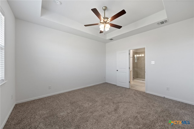 carpeted empty room featuring a tray ceiling and ceiling fan