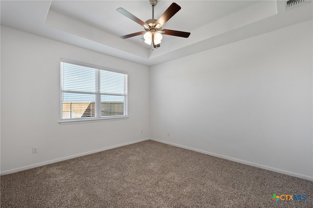 unfurnished room with carpet flooring and a tray ceiling