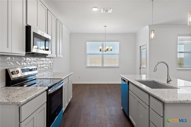 kitchen featuring decorative light fixtures, sink, light stone countertops, and stainless steel appliances