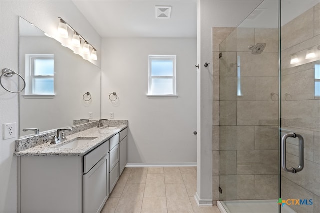 bathroom with tile patterned floors, vanity, an enclosed shower, and a wealth of natural light