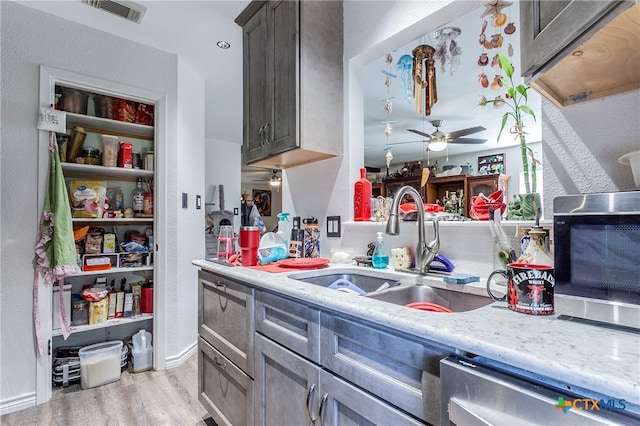 kitchen featuring stainless steel appliances, dark brown cabinetry, sink, ceiling fan, and light hardwood / wood-style flooring