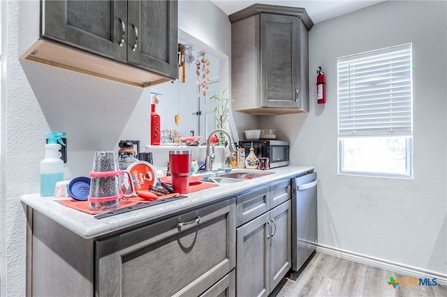 kitchen with dark brown cabinets, light wood-type flooring, stainless steel appliances, and sink