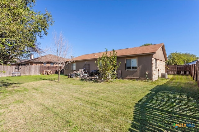 rear view of house with central AC and a yard