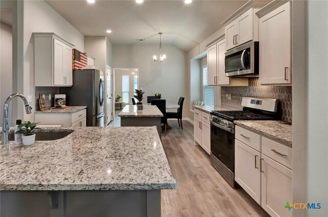 213 Flint Rock Ct, Victoria, TX 77904 - kitchen featuring stainless steel appliances, a center island, backsplash, lofted ceiling, and recessed lighting