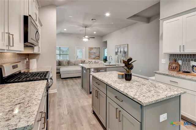 213 Flint Rock Ct, Victoria, TX 77904 - kitchen with appliances with stainless steel finishes, a kitchen island, open floor plan, gray cabinets, and light wood-style floors