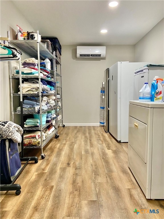 washroom with light wood-type flooring, a wall mounted AC, and washer / dryer