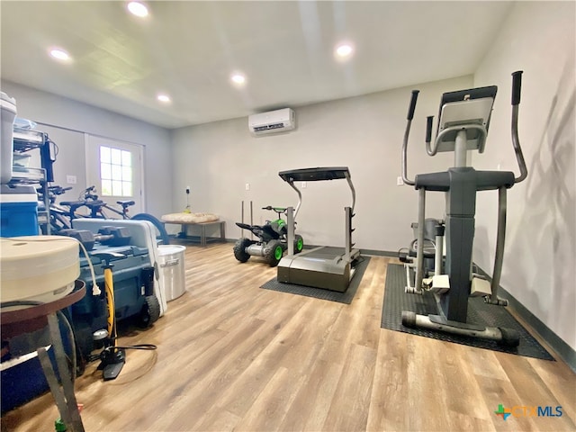 exercise area featuring a wall unit AC and light hardwood / wood-style flooring