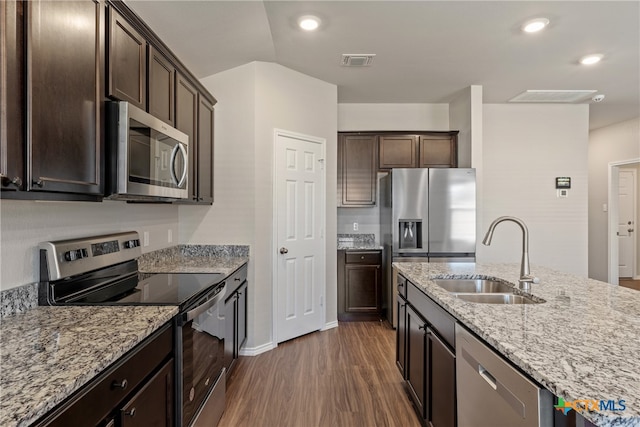 kitchen with light stone countertops, sink, dark wood-type flooring, stainless steel appliances, and dark brown cabinets