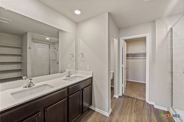 bathroom with toilet, a shower with door, vanity, and hardwood / wood-style flooring