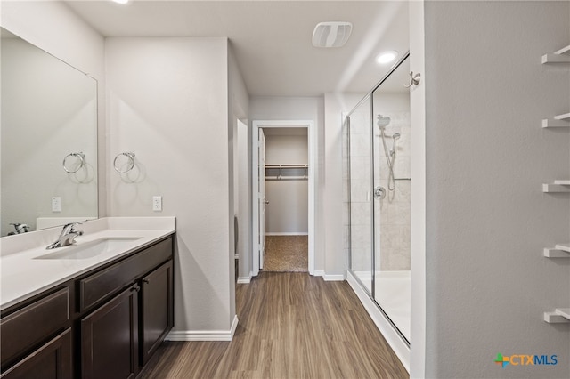 bathroom with walk in shower, vanity, and hardwood / wood-style flooring