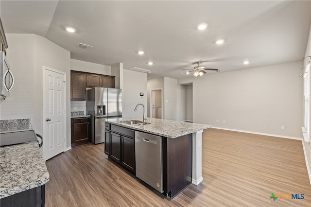 kitchen featuring sink, an island with sink, wood-type flooring, dark brown cabinets, and appliances with stainless steel finishes