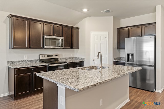 kitchen featuring sink, hardwood / wood-style floors, dark brown cabinets, a center island with sink, and appliances with stainless steel finishes