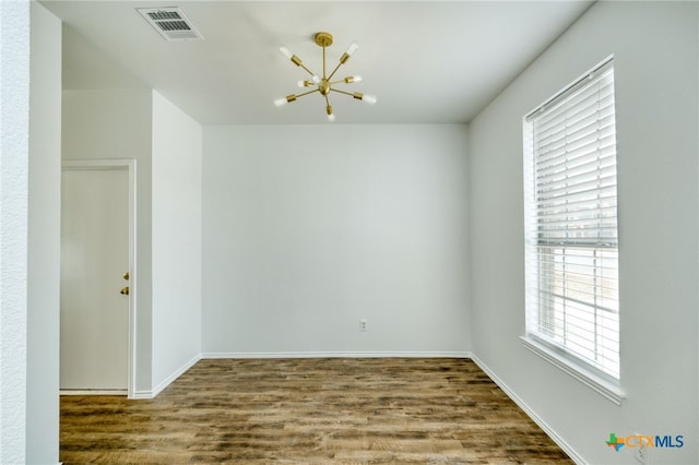 unfurnished room with a chandelier, hardwood / wood-style floors, and plenty of natural light