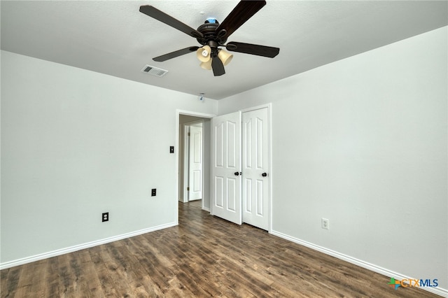 unfurnished bedroom featuring ceiling fan, dark hardwood / wood-style flooring, and a closet