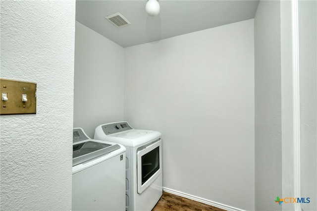 clothes washing area with washer and dryer and dark hardwood / wood-style flooring