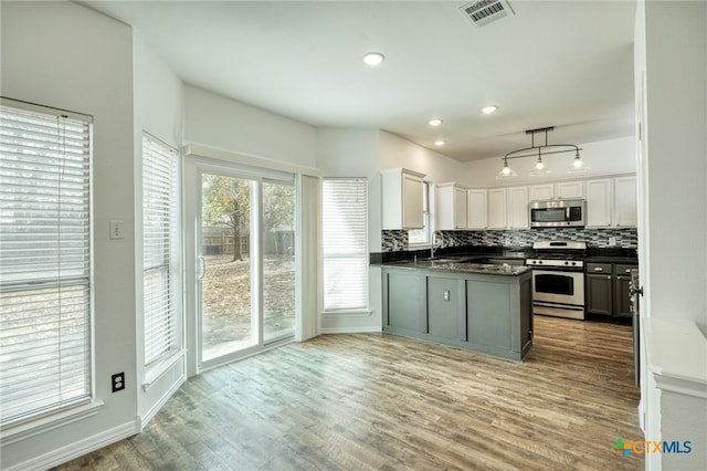 kitchen featuring decorative light fixtures, white cabinetry, stainless steel appliances, and a wealth of natural light