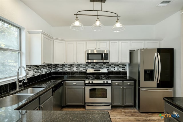 kitchen featuring white cabinets, sink, gray cabinets, appliances with stainless steel finishes, and decorative light fixtures