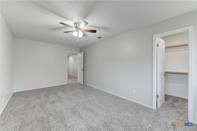 unfurnished bedroom featuring a walk in closet, carpet, visible vents, and baseboards