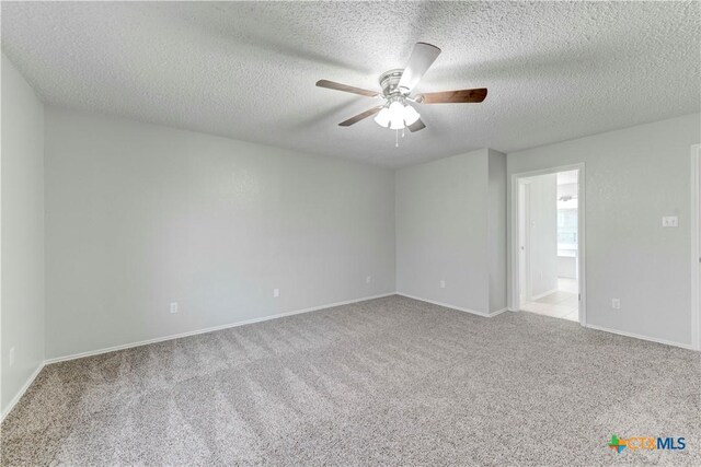 empty room featuring carpet flooring, a ceiling fan, baseboards, and a textured ceiling