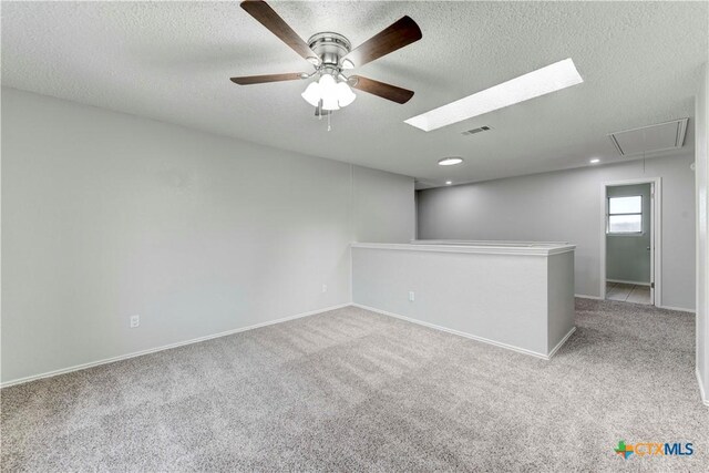 carpeted empty room featuring visible vents, a textured ceiling, attic access, and baseboards