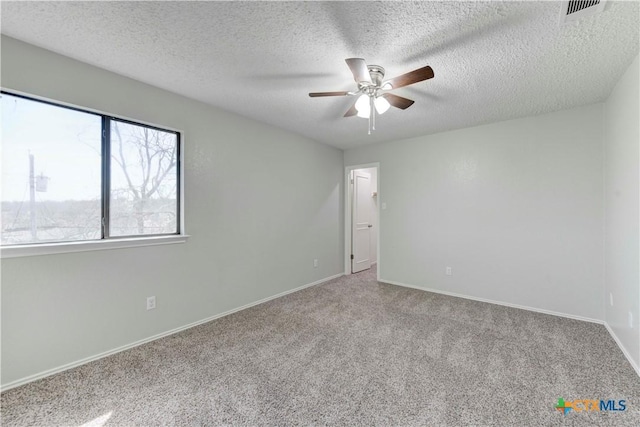 spare room with visible vents, a ceiling fan, a textured ceiling, carpet flooring, and baseboards