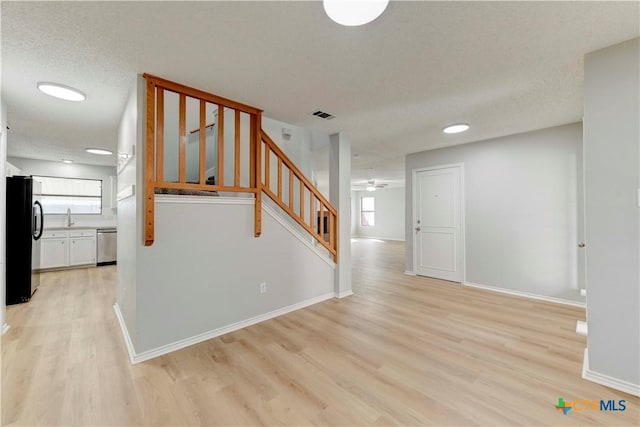 interior space featuring visible vents, a textured ceiling, baseboards, and wood finished floors