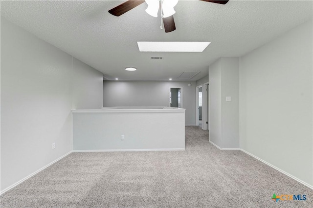 carpeted empty room featuring a ceiling fan, baseboards, visible vents, and a textured ceiling