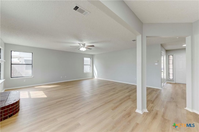 unfurnished living room featuring visible vents, baseboards, light wood-style floors, and a ceiling fan