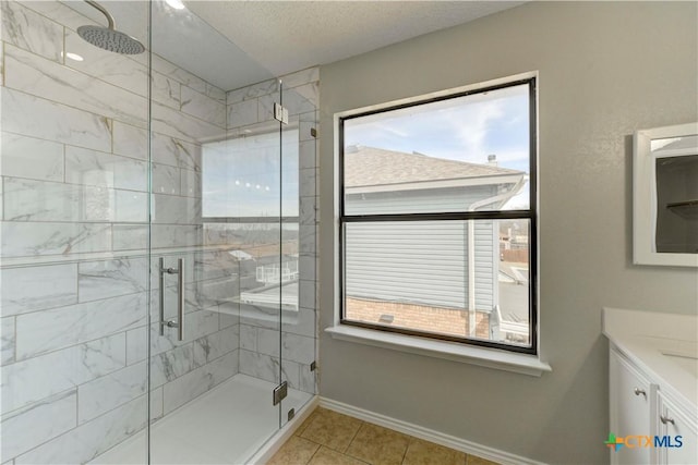 bathroom with a shower stall, baseboards, vanity, tile patterned floors, and a textured ceiling