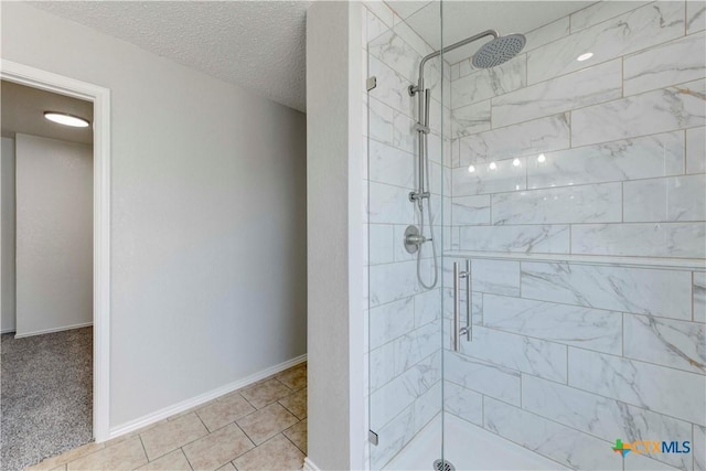 full bath featuring a shower stall, baseboards, and a textured ceiling