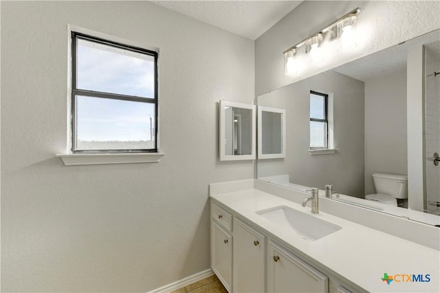 full bathroom featuring vanity, toilet, a healthy amount of sunlight, and a textured ceiling