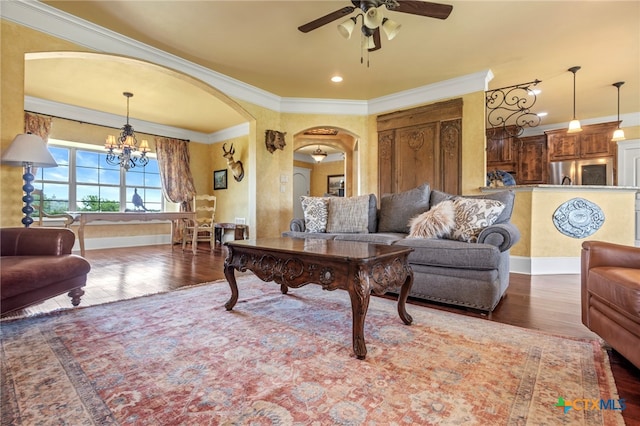 living room with ceiling fan with notable chandelier, crown molding, and dark wood-type flooring