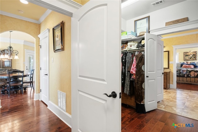 hallway featuring crown molding, dark wood-type flooring, and a notable chandelier