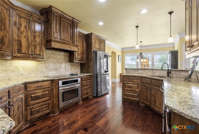 kitchen featuring pendant lighting, sink, dark hardwood / wood-style floors, ornamental molding, and appliances with stainless steel finishes