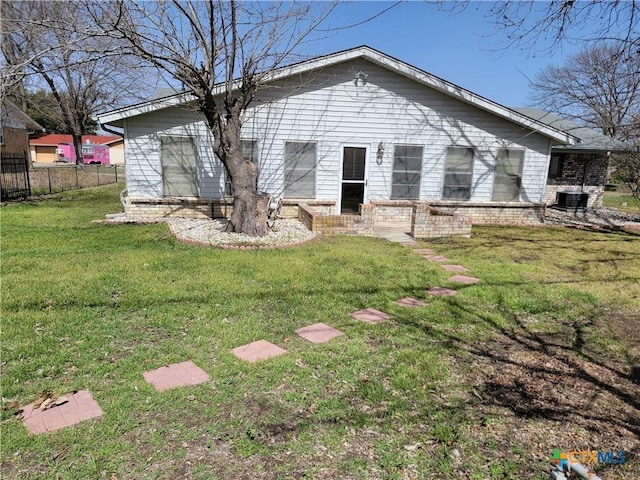 rear view of property featuring a yard, brick siding, and fence