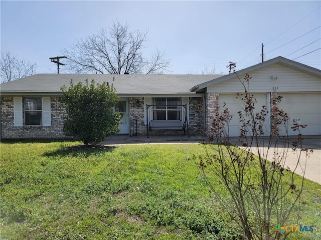 single story home featuring an attached garage, brick siding, driveway, and a front lawn