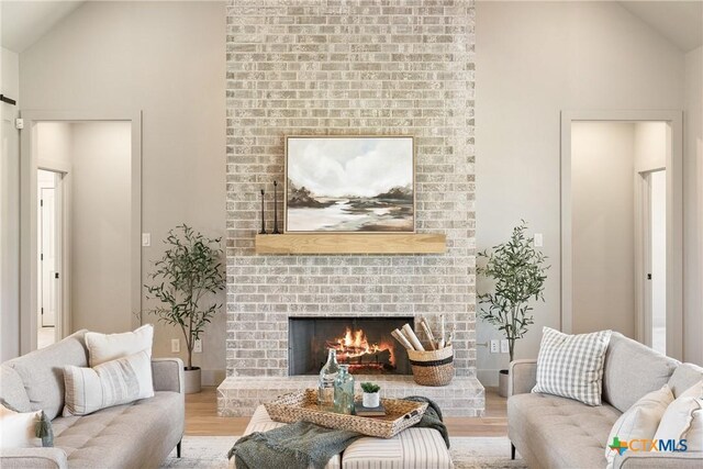 227 Glenview Cir, Belton, TX 76513 - living area featuring wood finished floors, a fireplace, high vaulted ceiling, and a barn door