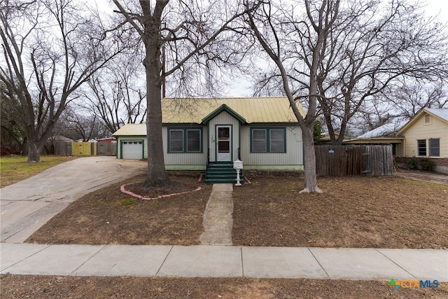 view of front of property with a garage, driveway, fence, and metal roof