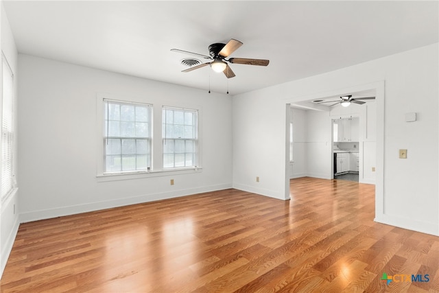 empty room featuring a ceiling fan, visible vents, light wood-style flooring, and baseboards