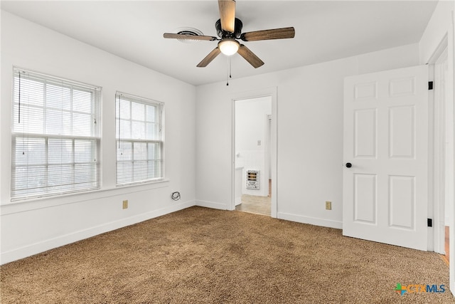 unfurnished bedroom with baseboards, carpet floors, ceiling fan, and heating unit