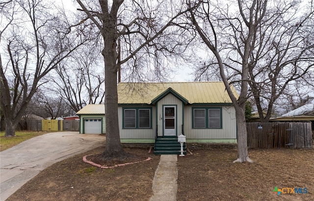 view of front of home featuring metal roof, driveway, an attached garage, and fence