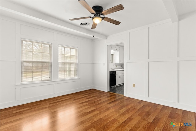 unfurnished bedroom with connected bathroom, a decorative wall, a sink, visible vents, and light wood finished floors