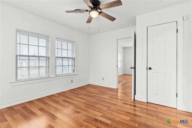 unfurnished bedroom featuring light wood-style flooring, baseboards, and a ceiling fan