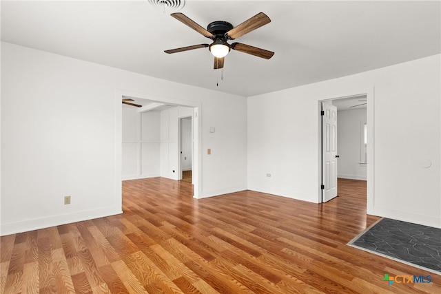 spare room featuring ceiling fan, visible vents, light wood-style flooring, and baseboards