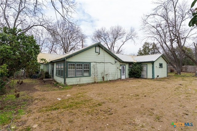 exterior space featuring a garage, metal roof, and fence